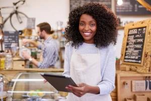 Imagem de uma mulher sorrindo em um estabelecimento comercial segurando um tablet